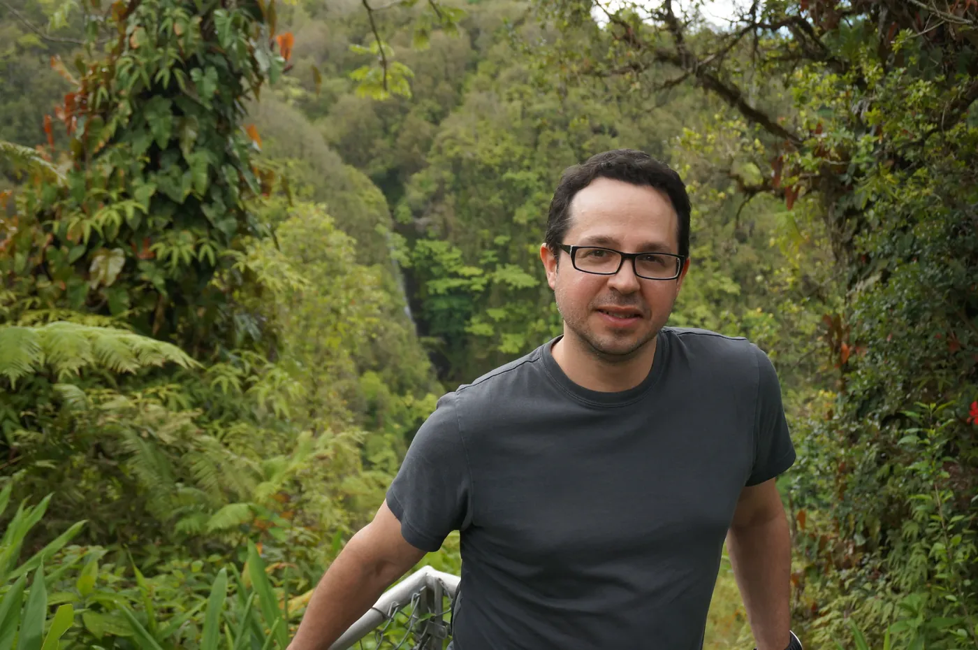 Federico Hatoum leaning on a railing in a lush green rainforest